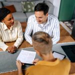 Couple consulting with female agent at their home