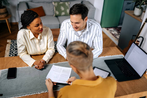 Couple consulting with female agent at their home